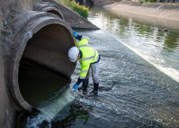 A service worker collects samples from a stormwater outlet.